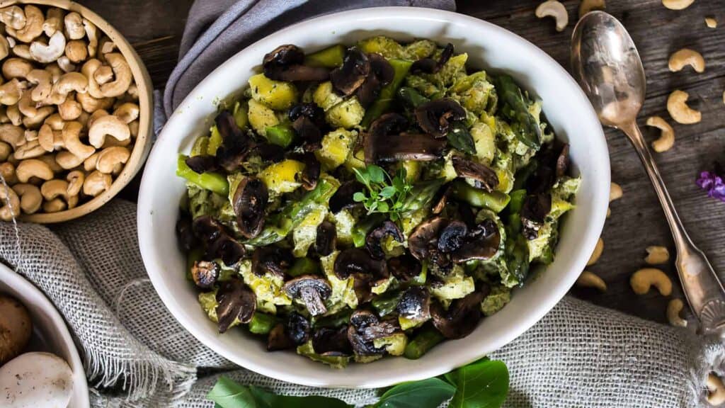 Mushrooms and cashews in a white bowl.