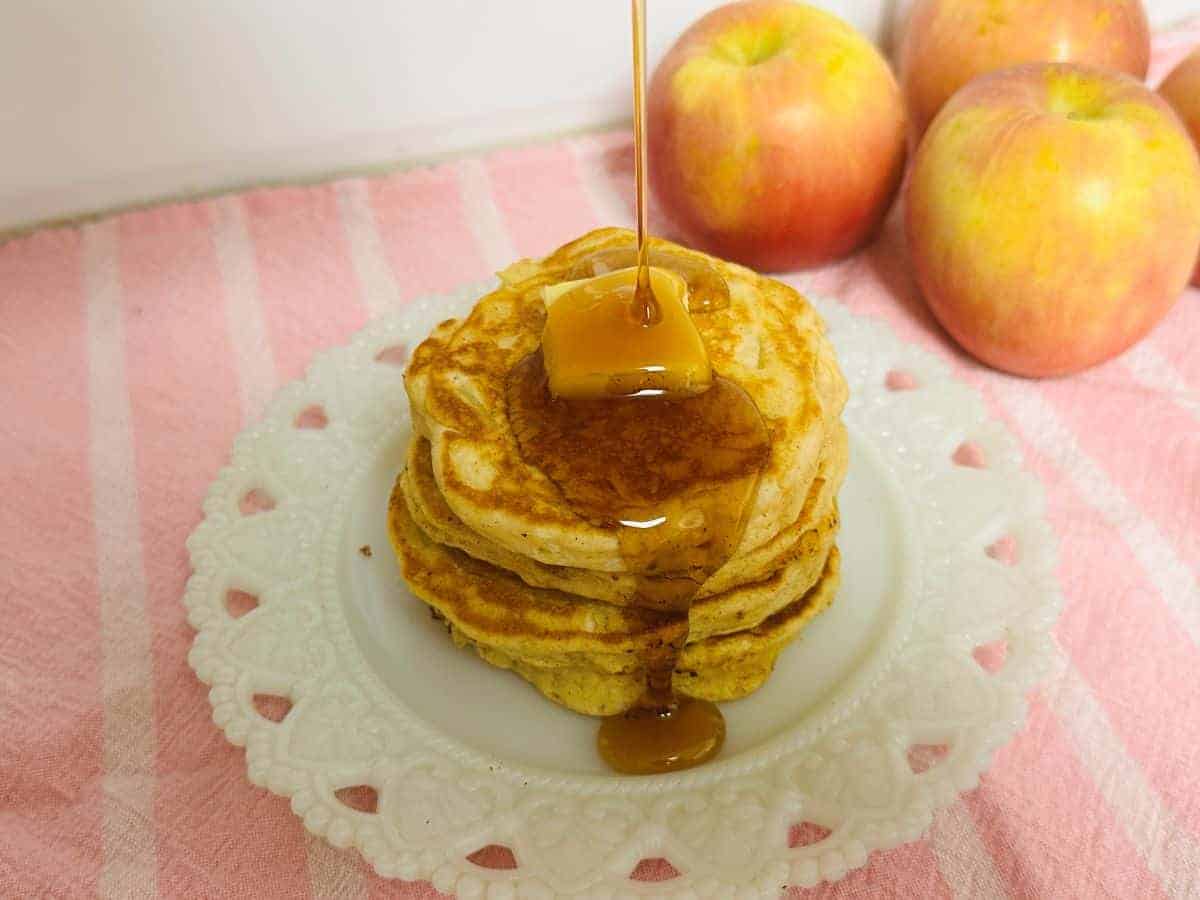 A stack of pancakes with syrup being poured over them.