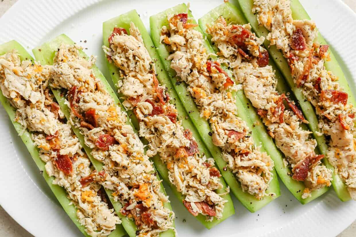 Bacon ranch chicken salad cucumber boats lined up on a plate.