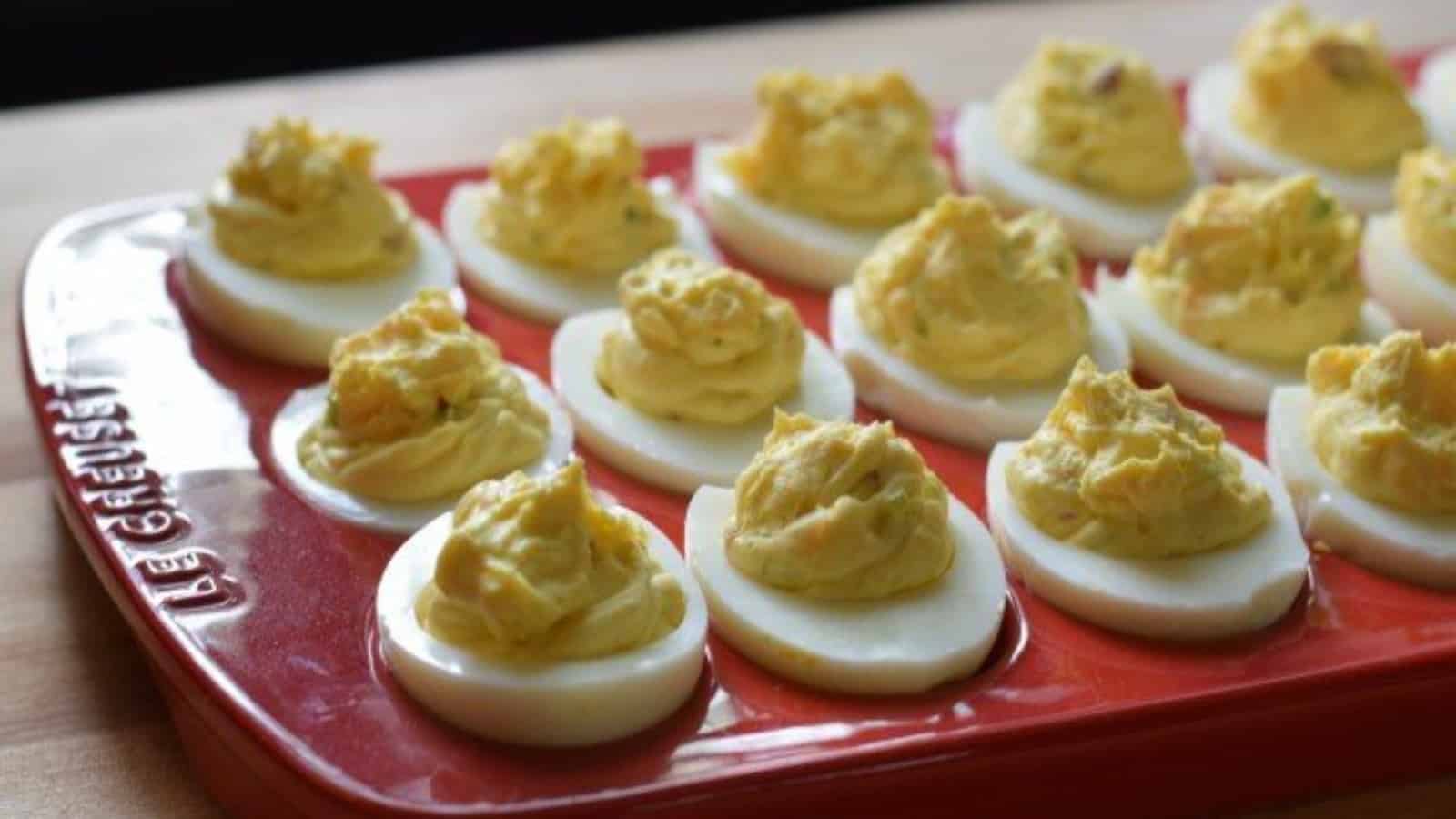 Image shows bacon deviled eggs in a red tray.