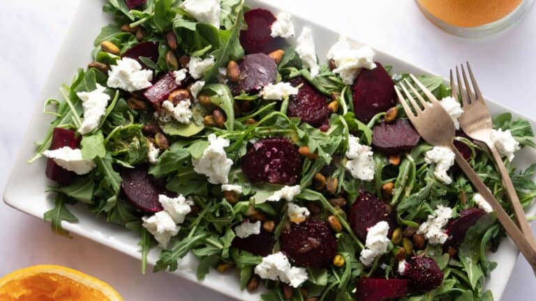 Beet salad on bed of arugula, goat cheese and pistachios.