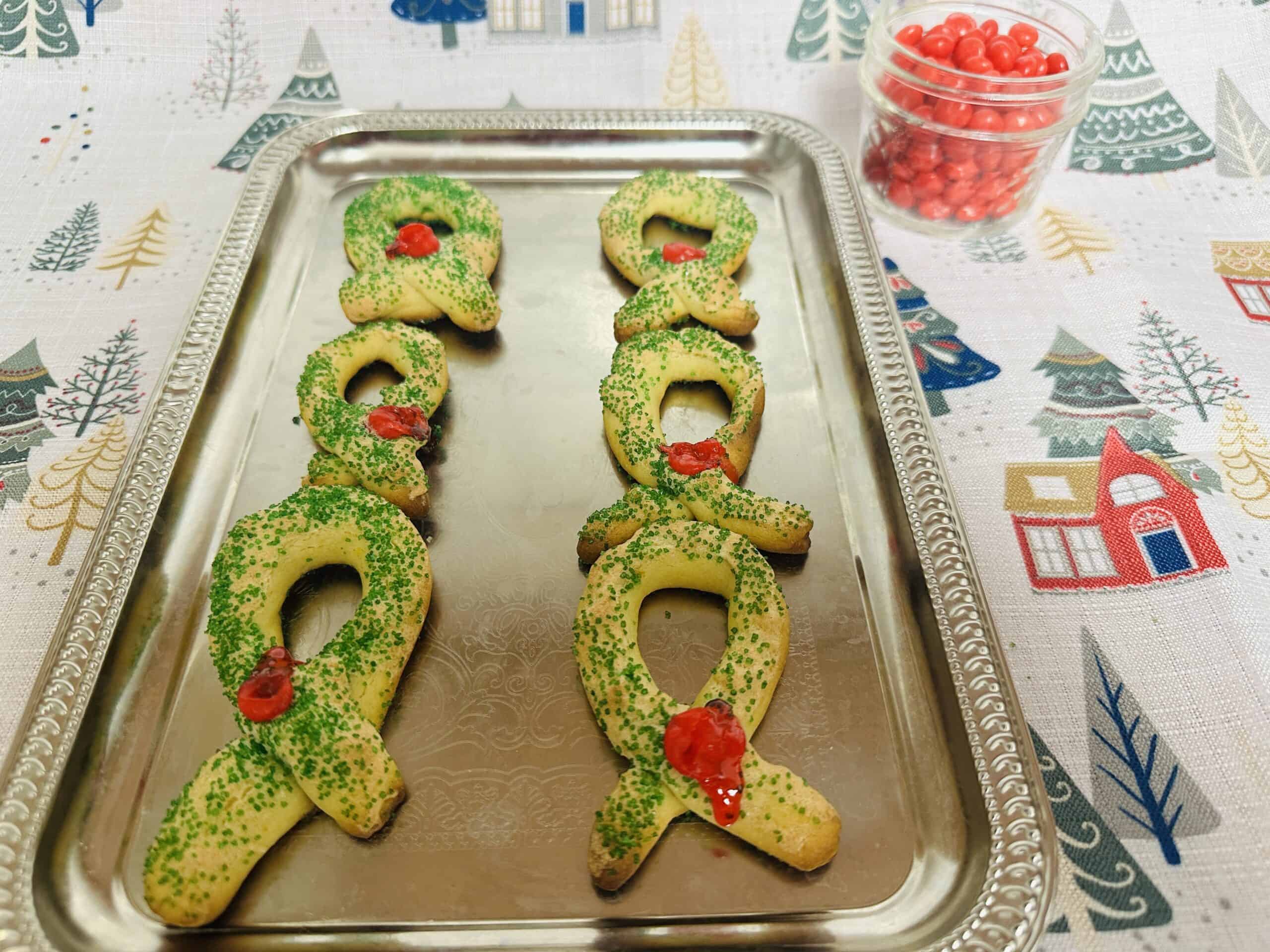 A tray of christmas cookies with green ribbons on it.