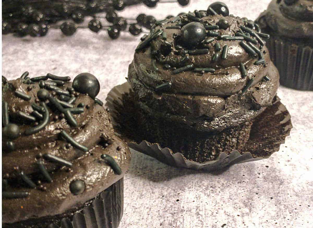 A group of black cupcakes decorated with black frosting.