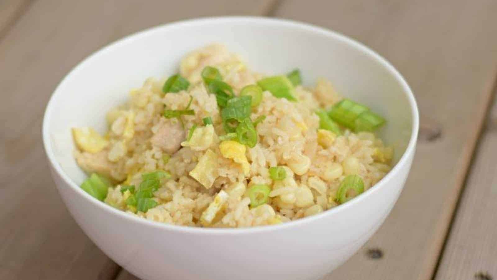 Images shows a white Bowl of chicken fried rice.