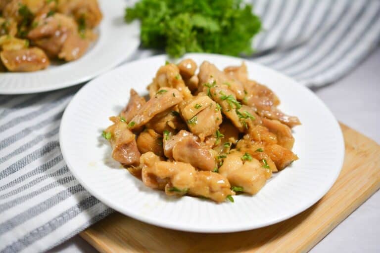 A white plate with chicken and parsley on it.