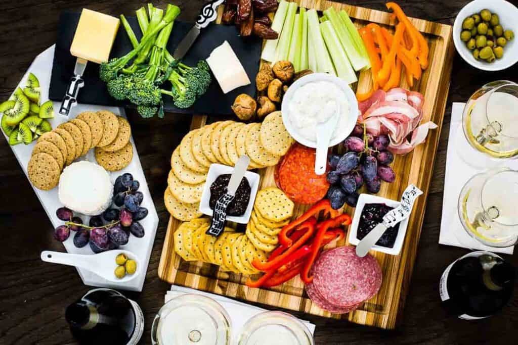 Festive holiday appetizers, consisting of a platter adorned with an assortment of cheese, crackers, and vegetables, elegantly arranged on a rustic wooden board.