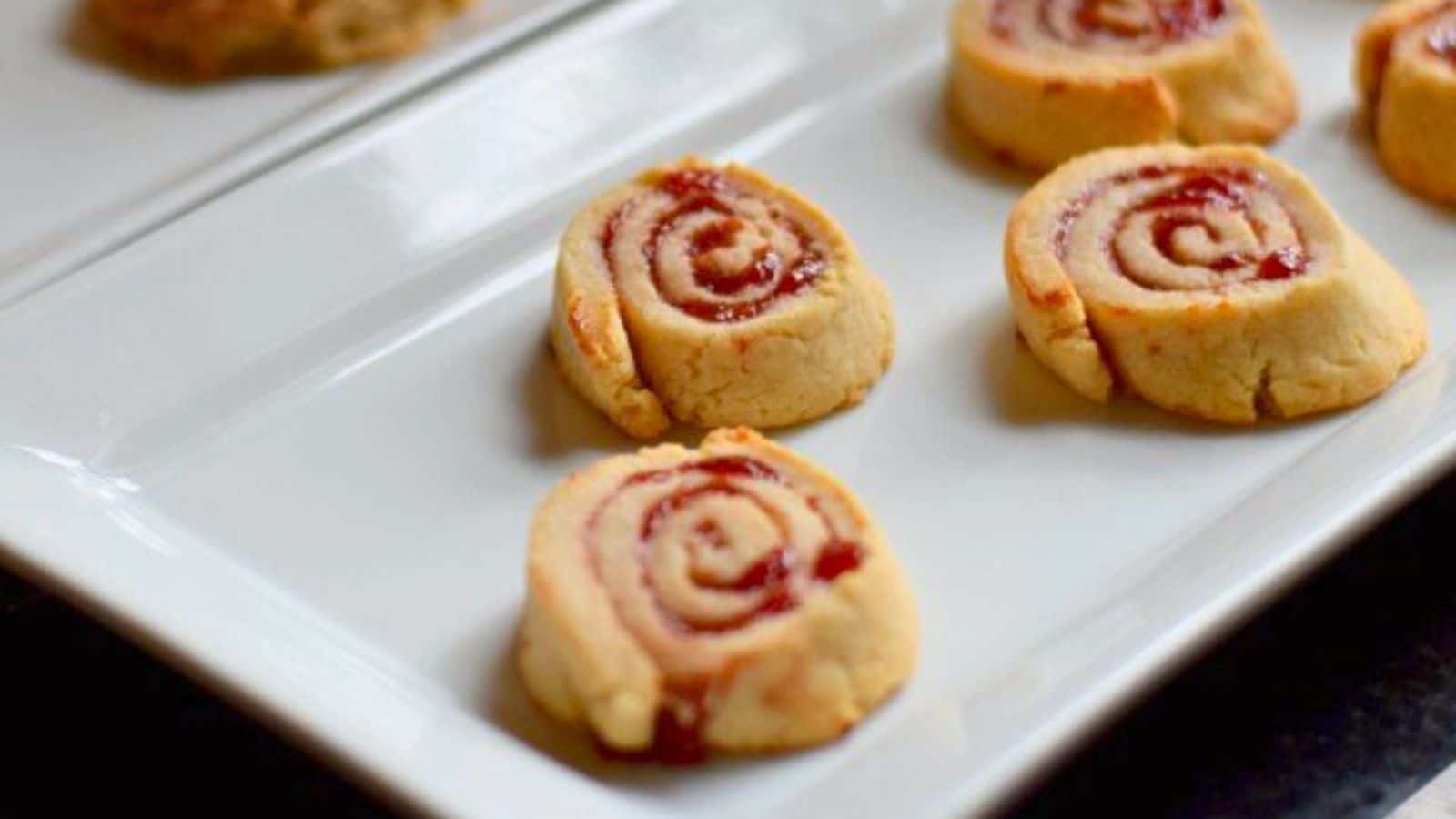 Image shows a plate with cherry pie pinwheel cookies sitting on it.