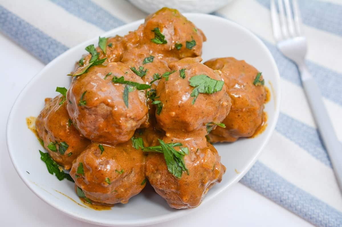 Chicken meatballs in a white bowl with a fork.