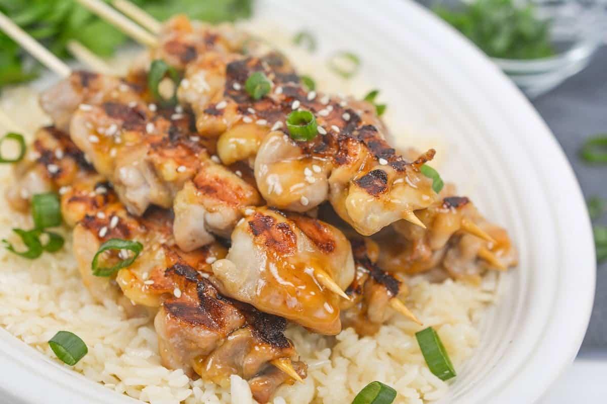 Asian chicken skewers on top of rice.
