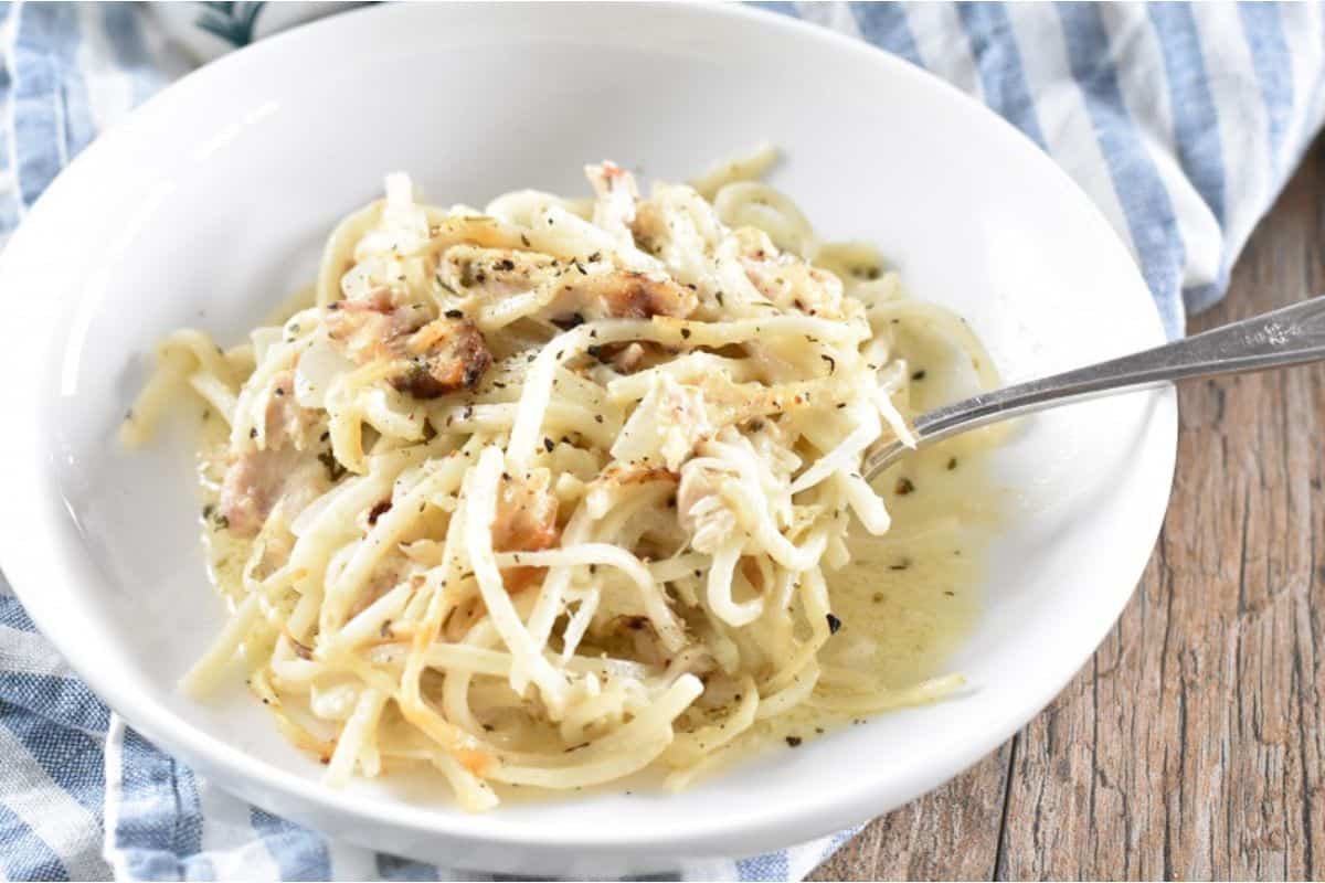 A bowl of pasta with chicken and parmesan cheese.