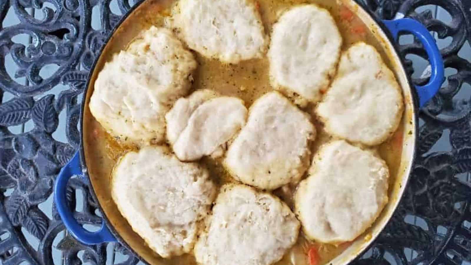 Image shows an overhead shot of Chicken stew with biscuits in a blue ceramic enameled pot.