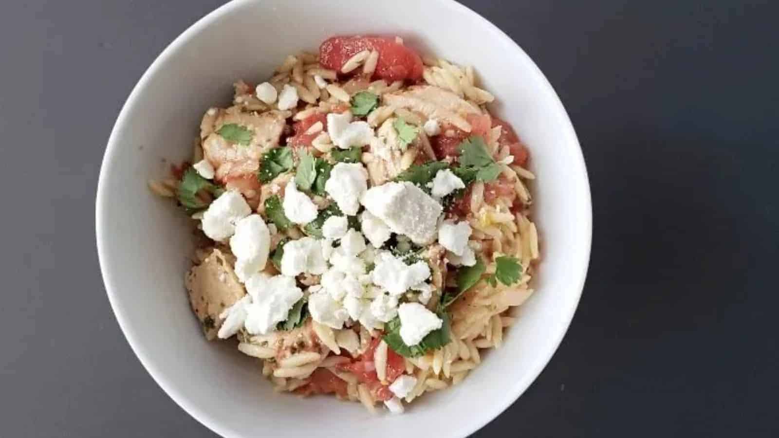 Image shows a closeup view of tuna and tomato pasta in a white patterned bowl.