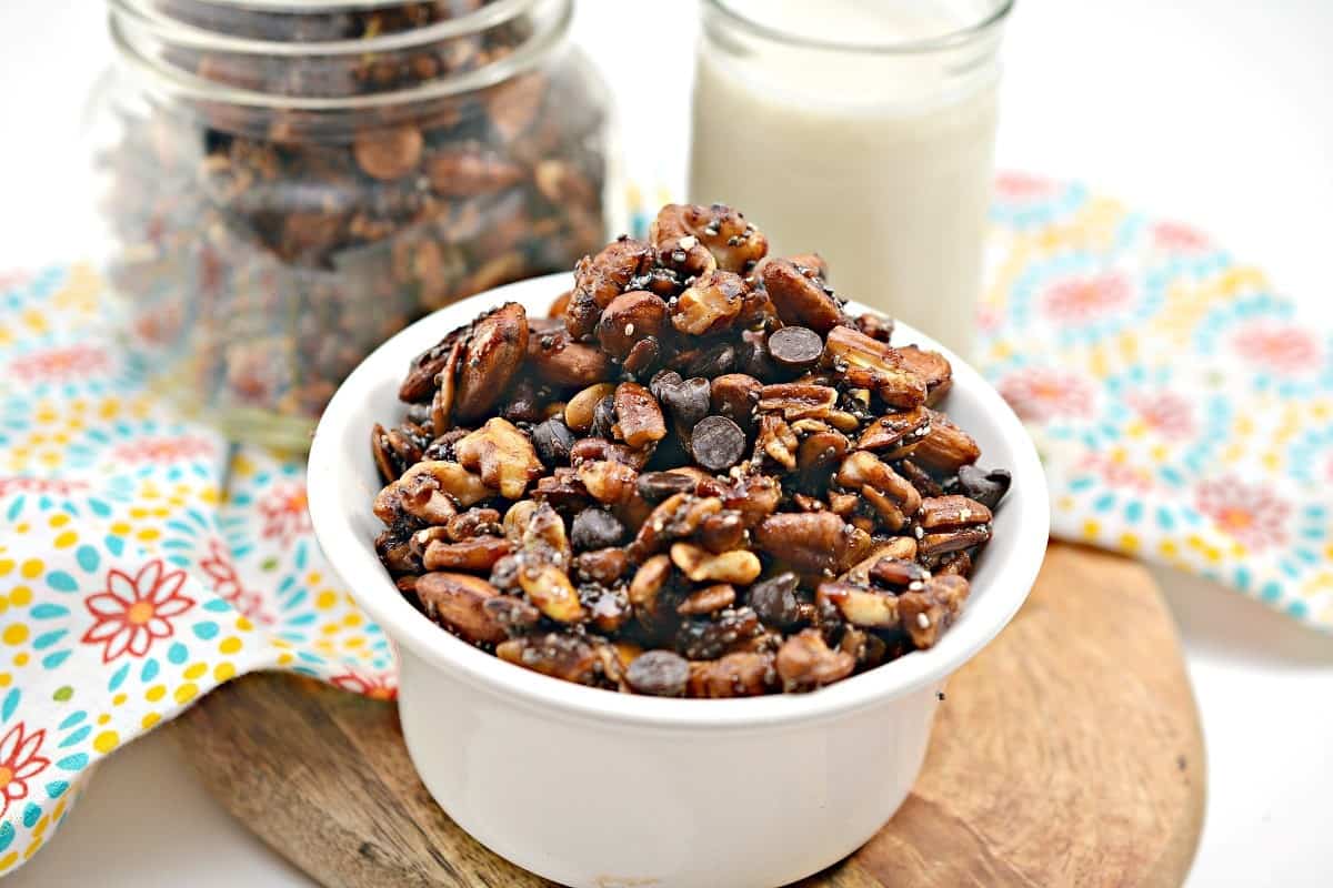 Chocolate pecan granola in a bowl next to a glass of milk.