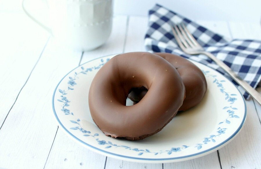 Two chocolate glazed donuts on a plate.