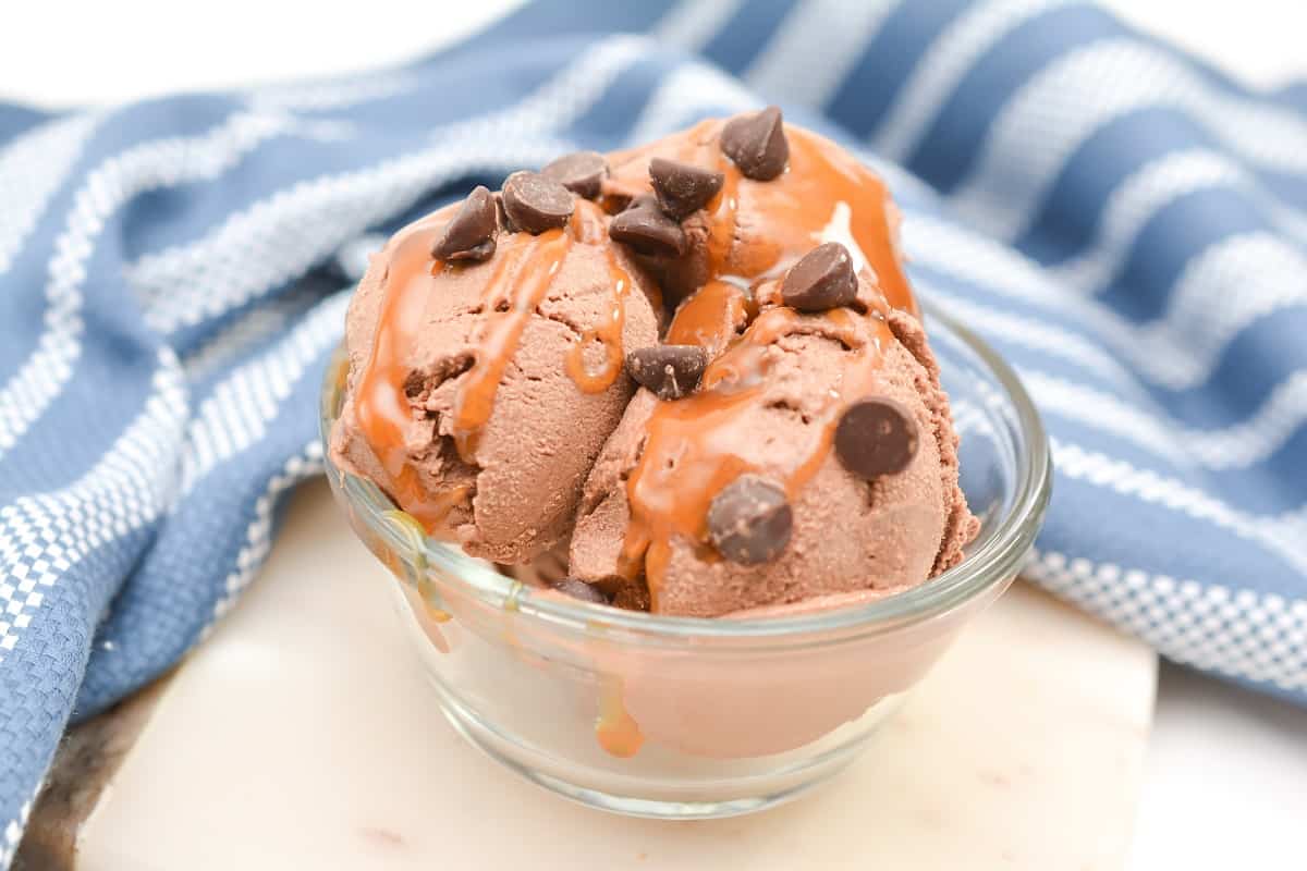 A bowl of chocolate ice cream with caramel and chocolate chips.