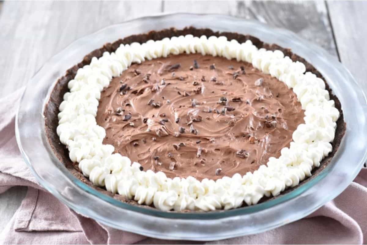 A chocolate pie with white icing on top.