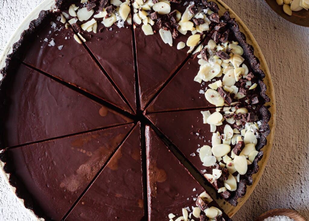         A chocolate tart with a slice taken out of it, perfect for pie and tart lovers.