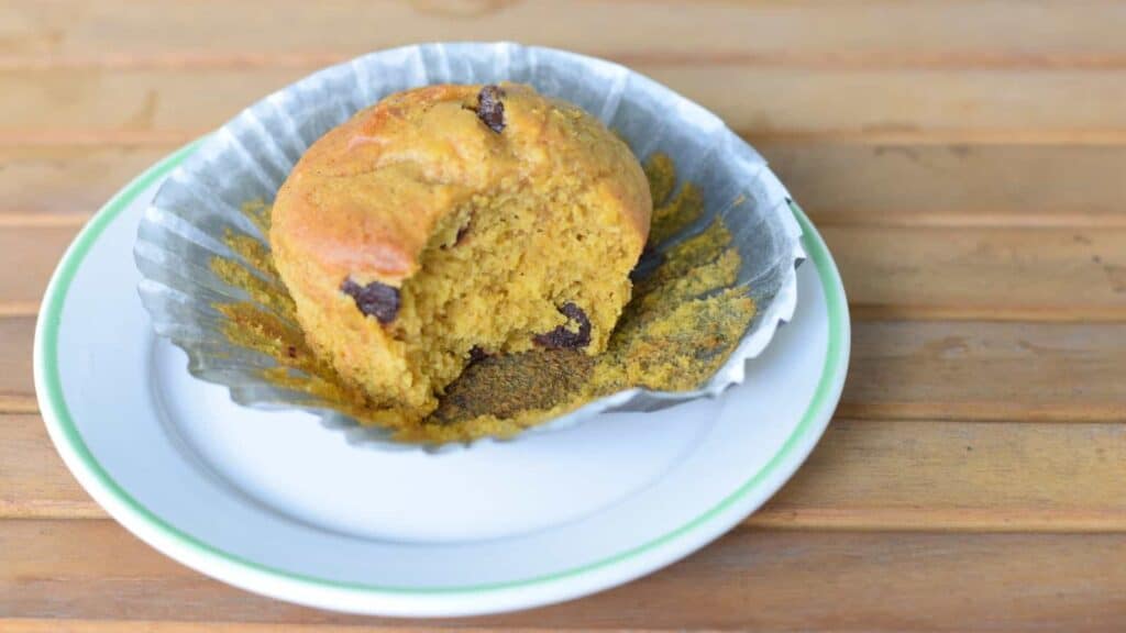 A muffin on a plate with a bite taken out of it.