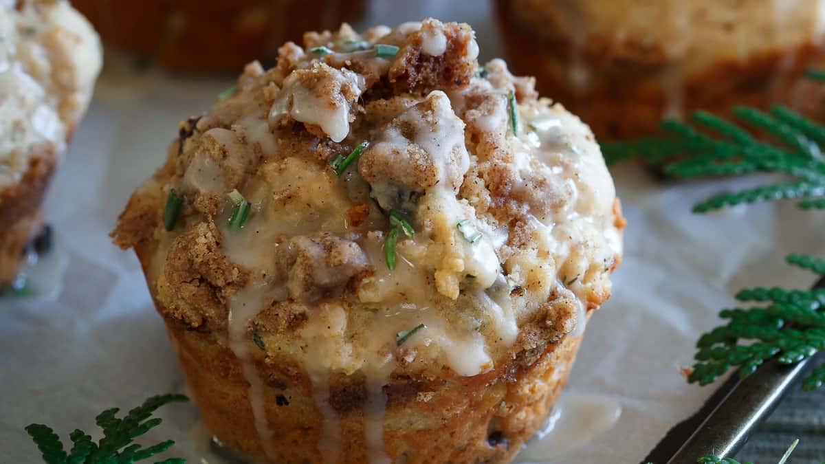 Muffins with cranberries and icing on a piece of paper.