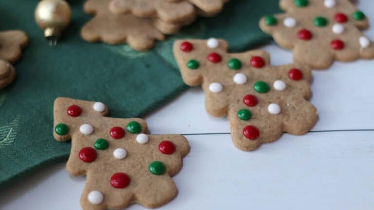 Gingerbread cookies decorated with red and green sprinkles on a green cloth.