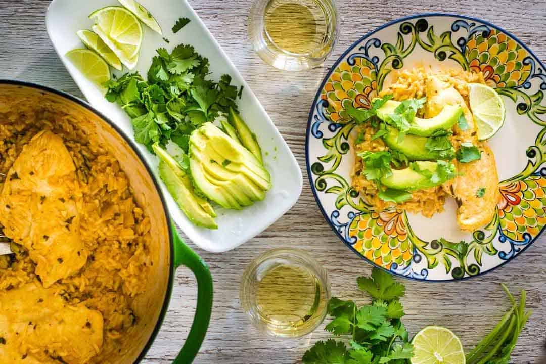 A bowl of rice and a bowl of guacamole on a wooden table.