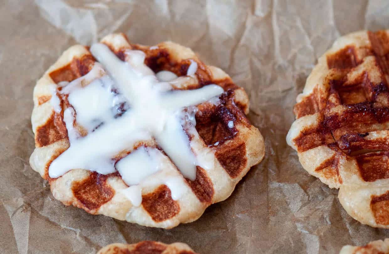 Cinnamon roll waffles with frosting on a baking sheet.