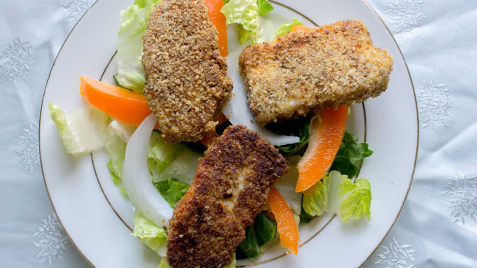 Hanukkah recipes for fried fish sticks with salad on a plate.