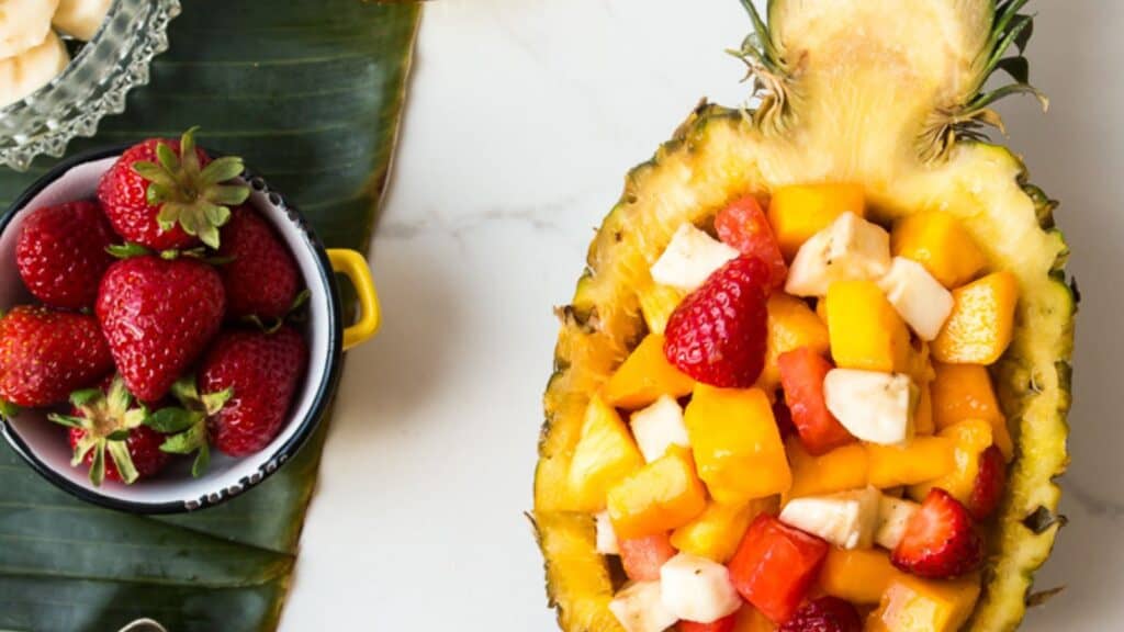 An easy breakfast of a pineapple filled with fruit and bananas.