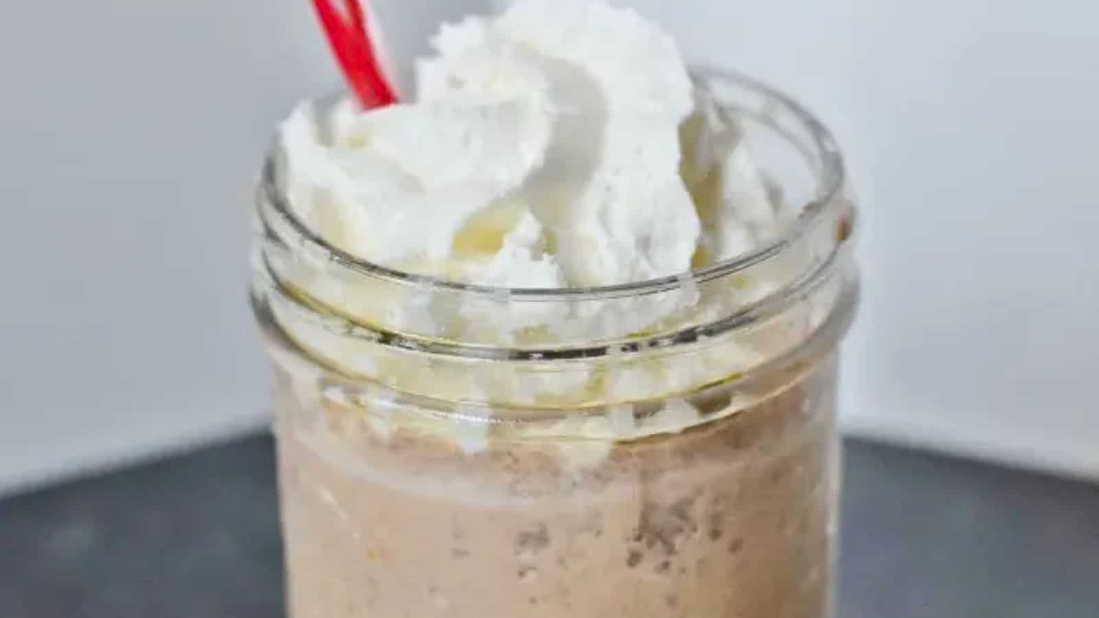 Image shows a closeup of a Copycat Java Chip Frappuccino in a mason jar with whipped cream and a straw.