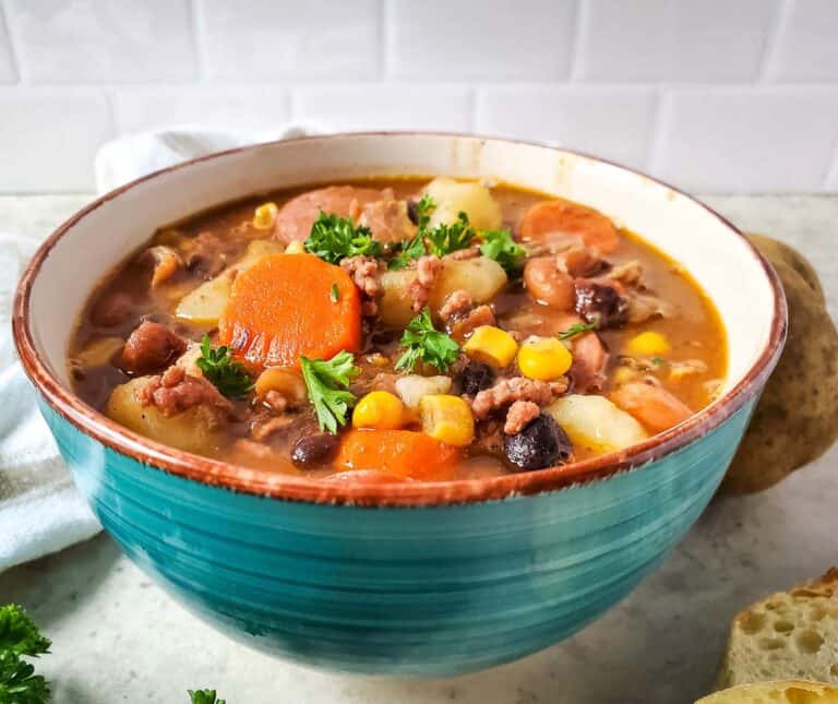 A bowl of stew with potatoes, carrots and beans.