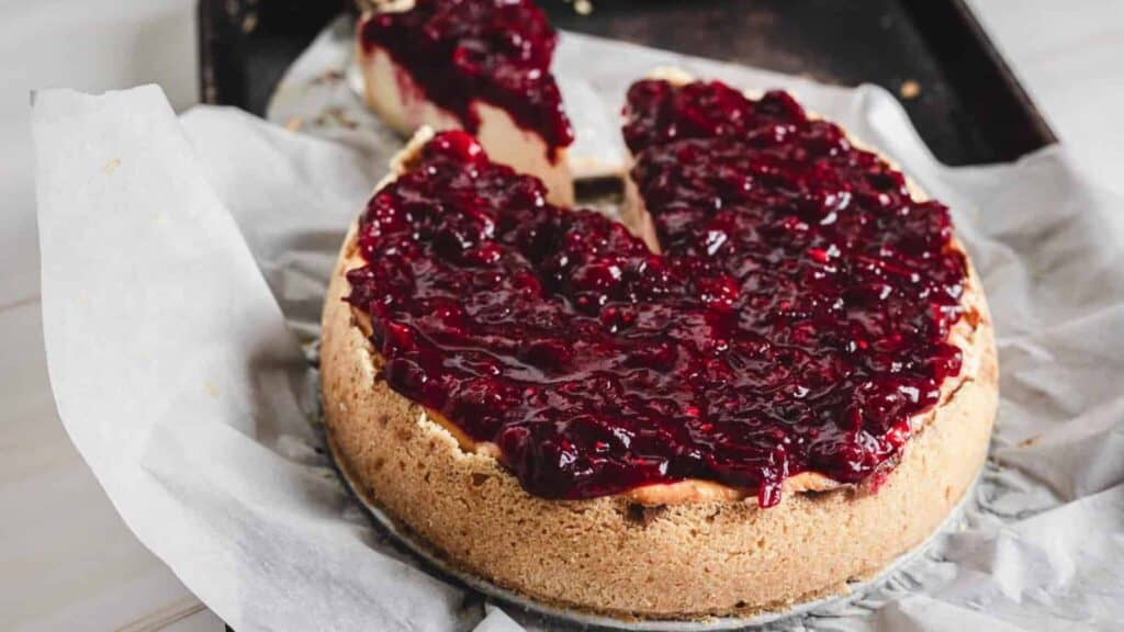 A slice of cheesecake with cranberry sauce on top.