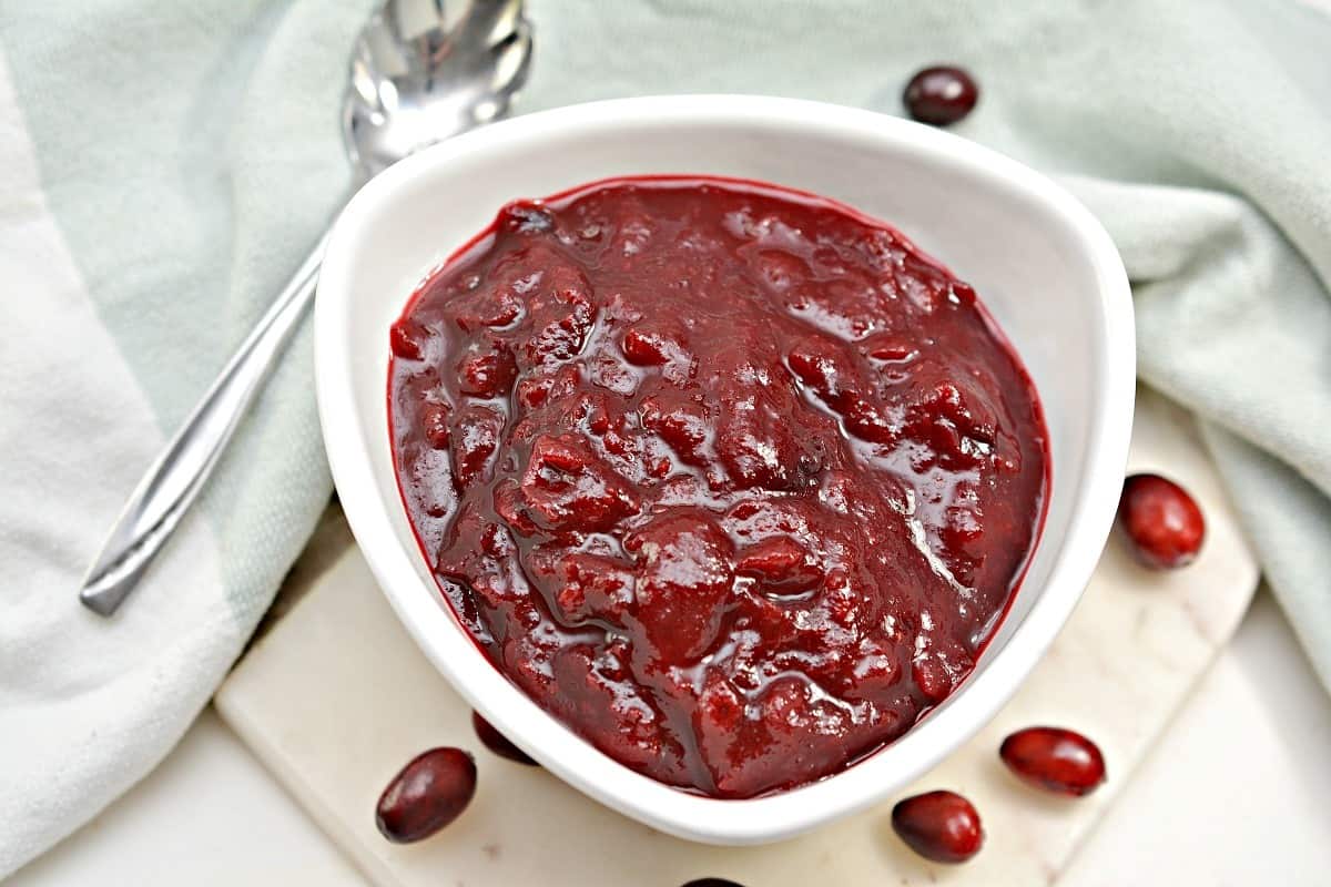 Cranberry sauce in a white bowl with cranberries.