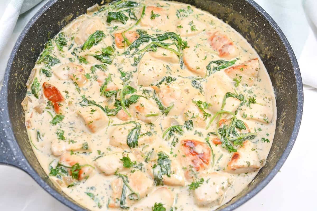 A skillet filled with chicken and spinach.