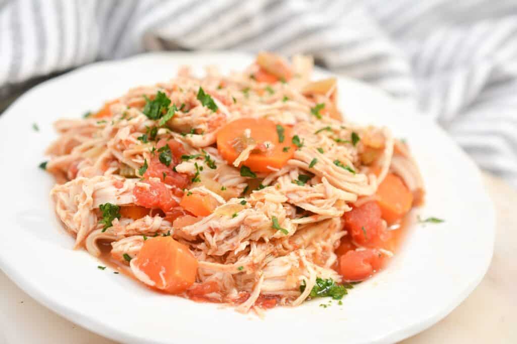 A white plate with chicken and carrots on it.