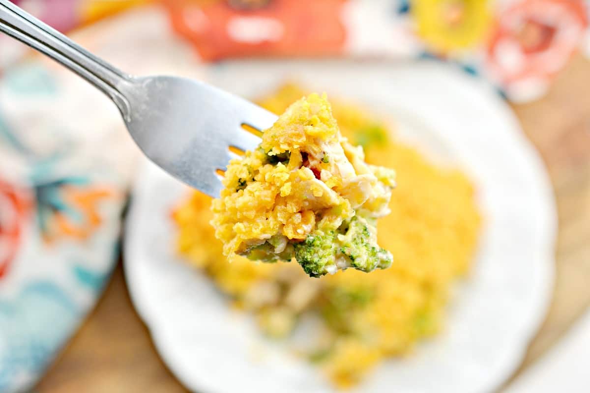 A fork is holding a piece of chicken and broccoli casserole.