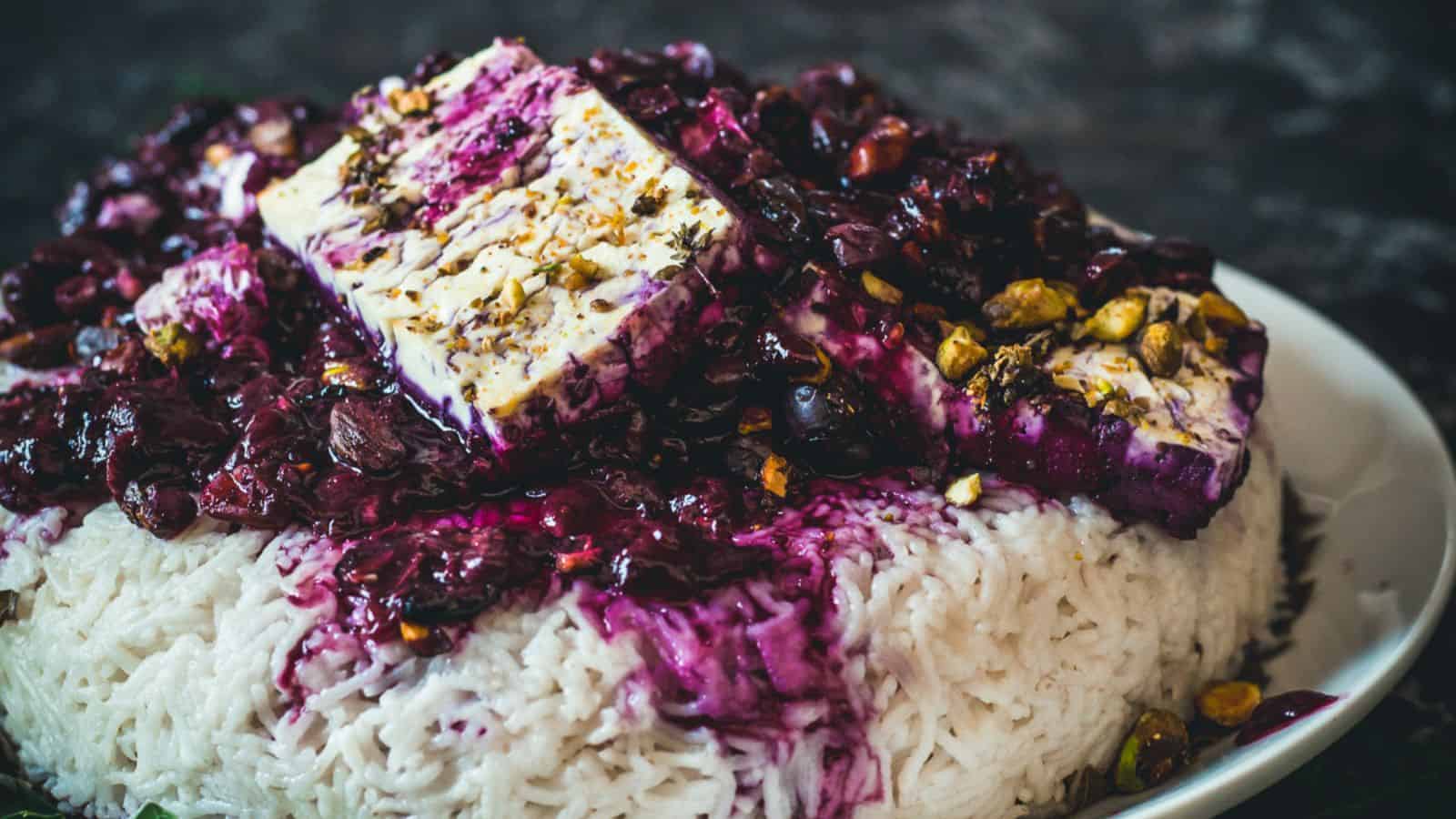 A plate of rice topped with blueberry sauce and tofu.