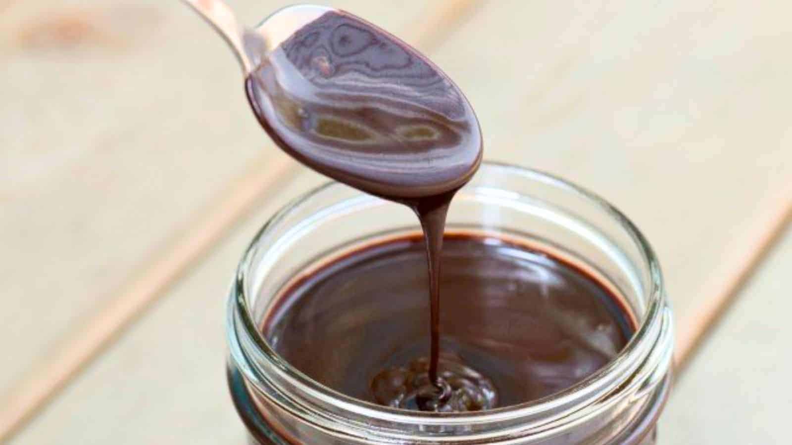 Image shows  A spoon is pouring espresso hot fudge sauce into a jar.