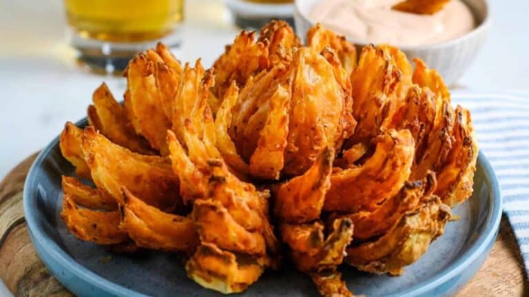 Fried onion rings on a plate with dipping sauce.