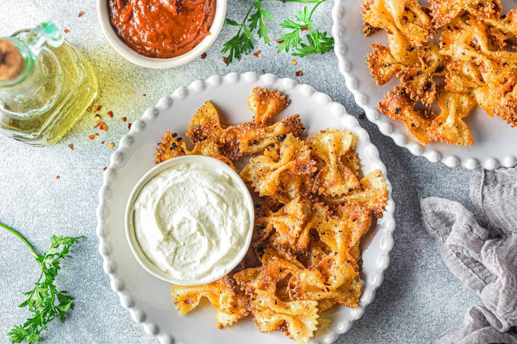 Crispy pasta chips on a plate with sauce.