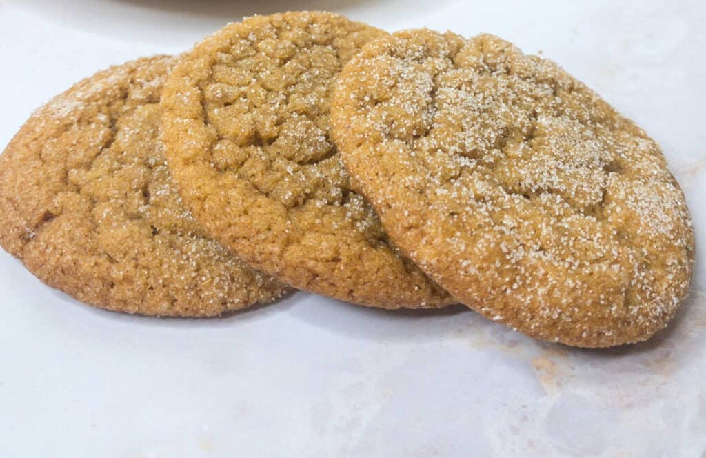 Three sugar cookies are sitting on a white plate.