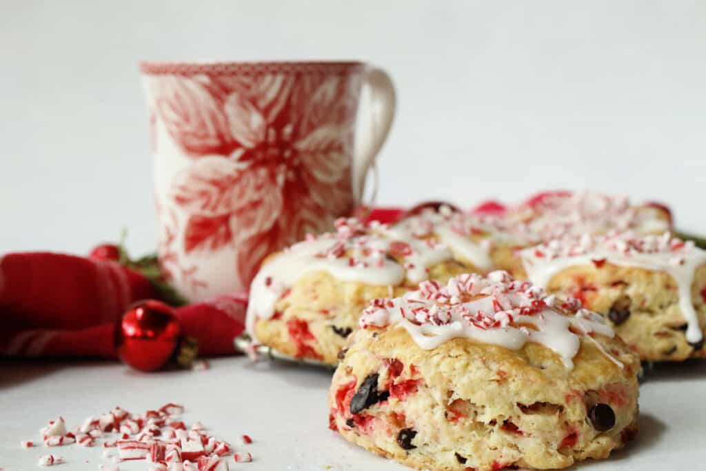 A plate of scones with icing and candy canes.