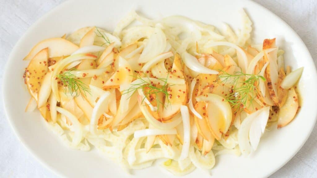 A white plate with onions and dill on it.