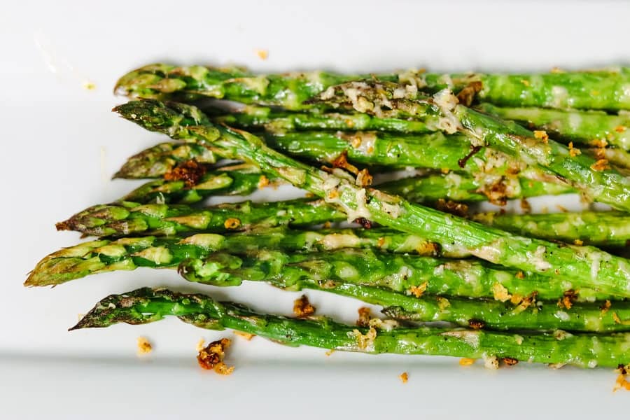 Roasted asparagus with garlic and parmesan on a white plate.
