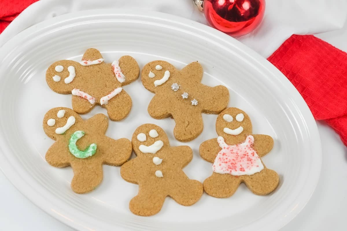 Gingerbread cookies on a plate with red and white decorations.