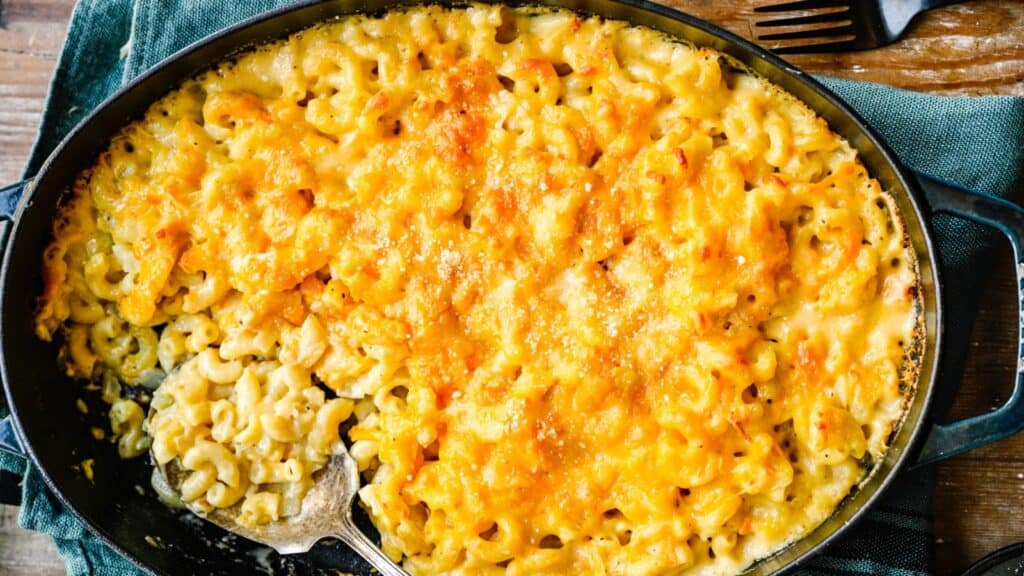 Close up of mac and cheese with a serving spoon in platter.