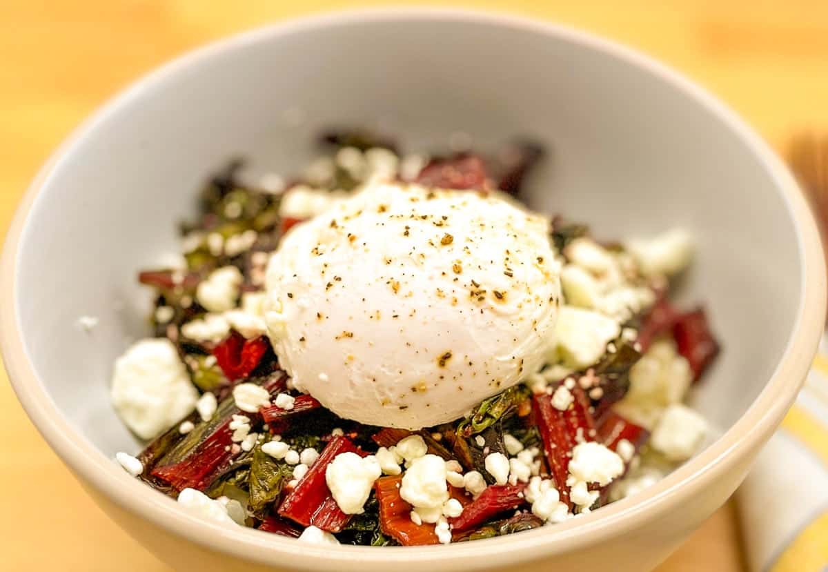 A bowl of beet salad with a poached egg on top.