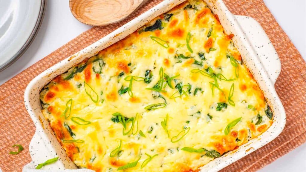 A casserole dish with spinach and cheese in it.