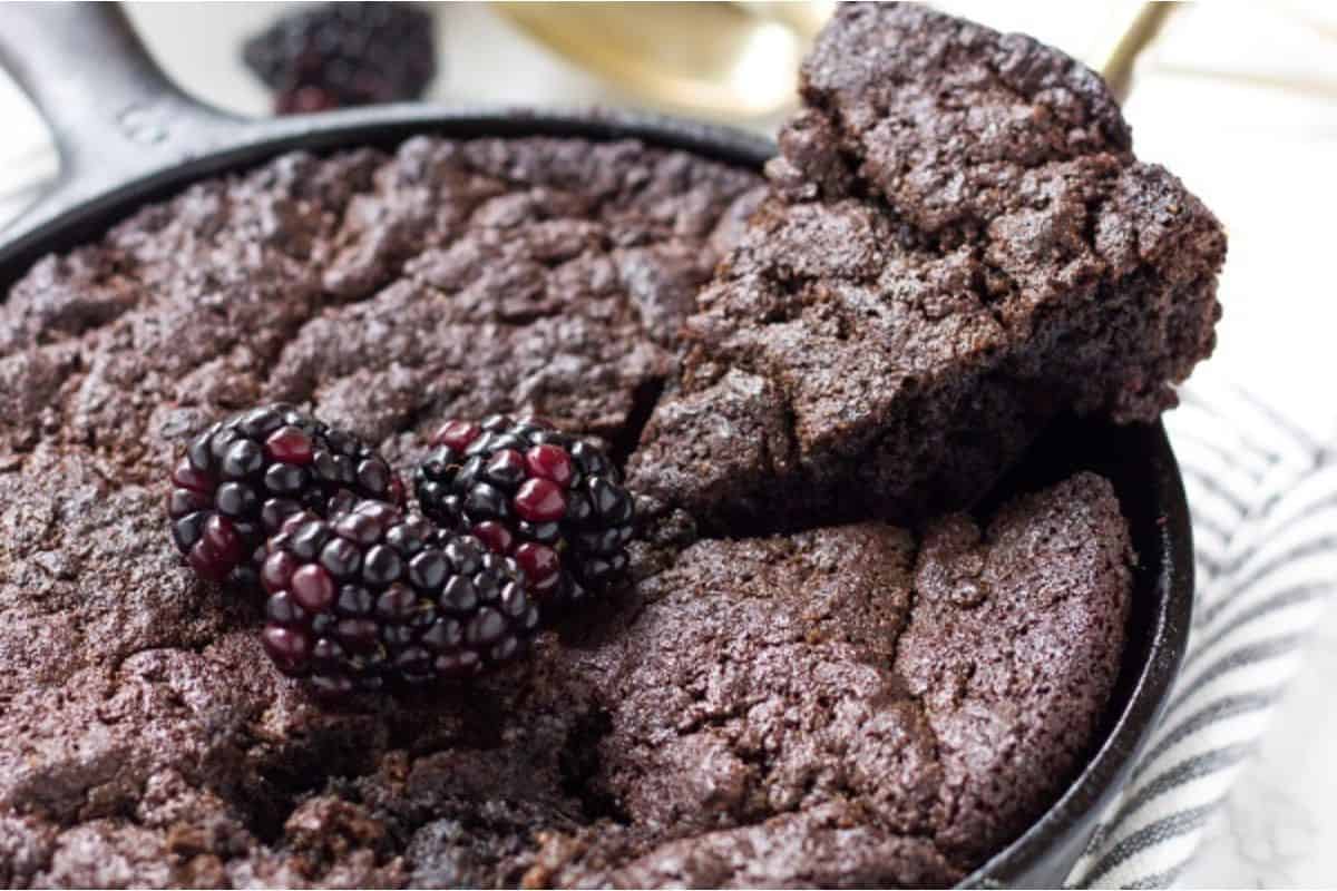 A chocolate cake with blackberries in a skillet.