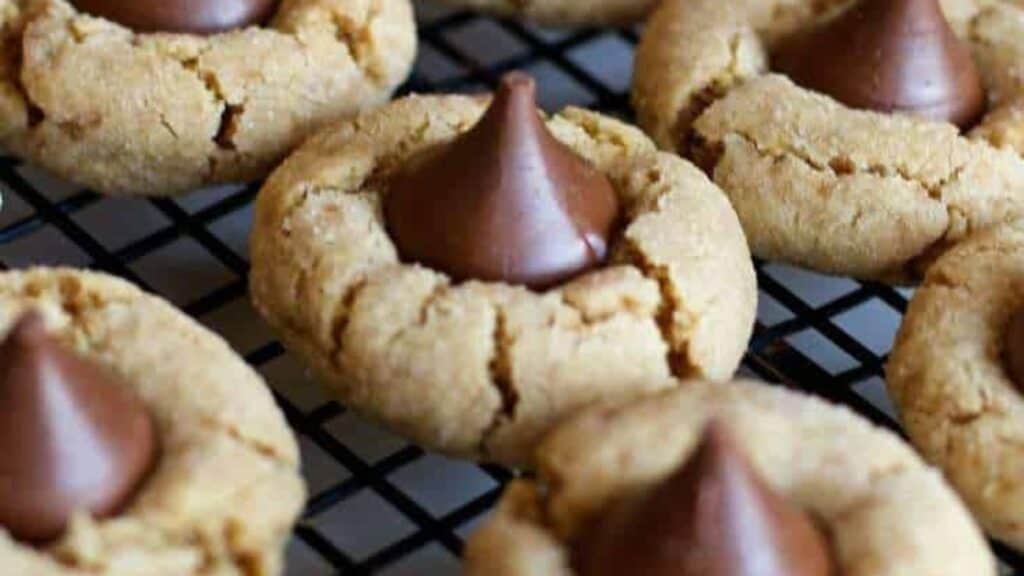 Peanut butter cookies with chocolate kisses on a cooling rack, creating naughty-but-nice cookies.