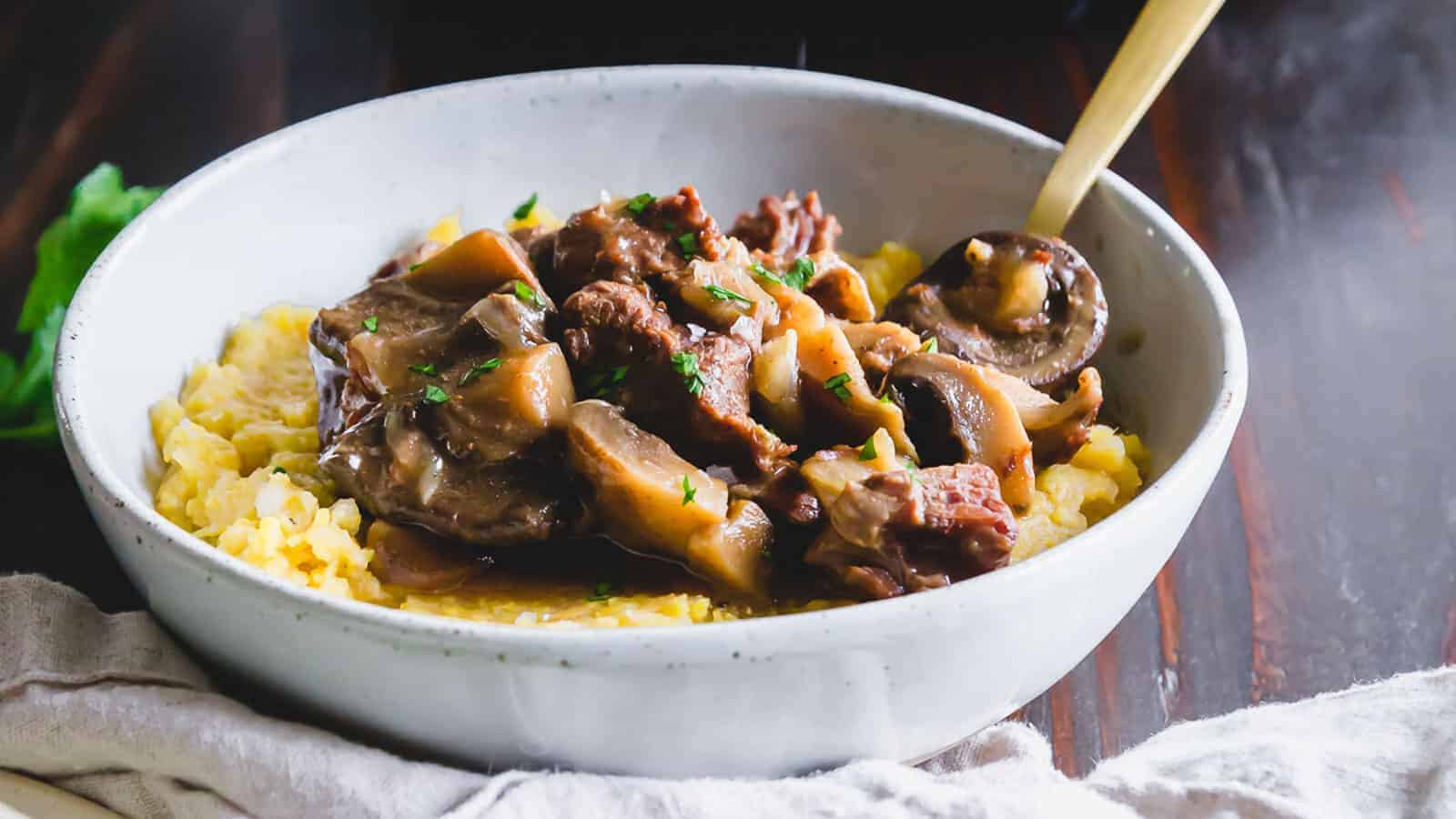 Instant Pot beef and mushroom stew served in a bowl over polenta.